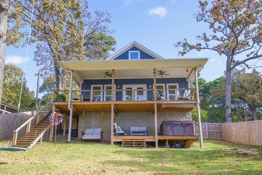 Back of house with board and batten siding, ceiling fan, stairs, and a hot tub