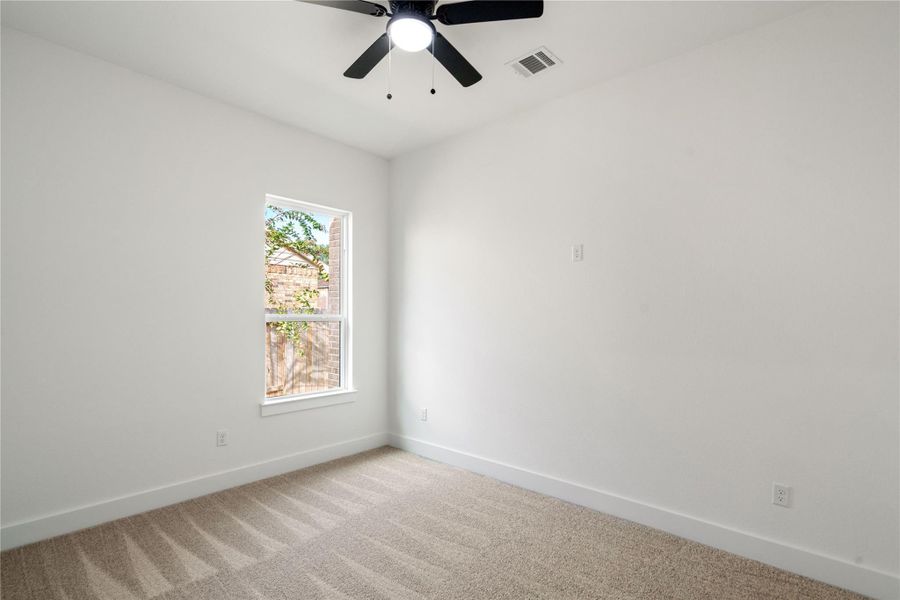 Cozy third bedroom with soft carpeting and natural light, perfect for a guest room or home office.