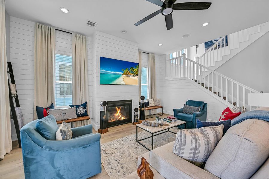 Multiple seating areas and oversized windows create a living room designed for gathering and relaxing. The bright coastal palette keeps the space feeling fresh and inviting.