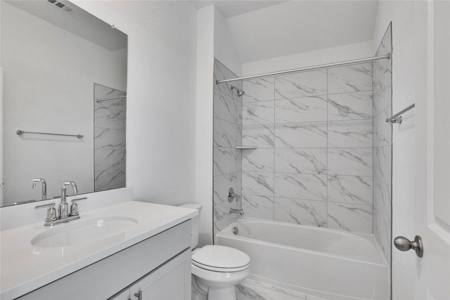 Full bath featuring shower / bath combination, vanity, and light marble finish floors Full bath featuring shower / bath combination, vanity, and light marble finish floors