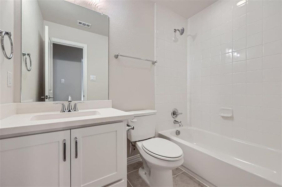 Full bathroom featuring vanity, tiled shower / bath combo, toilet, and tile patterned floors