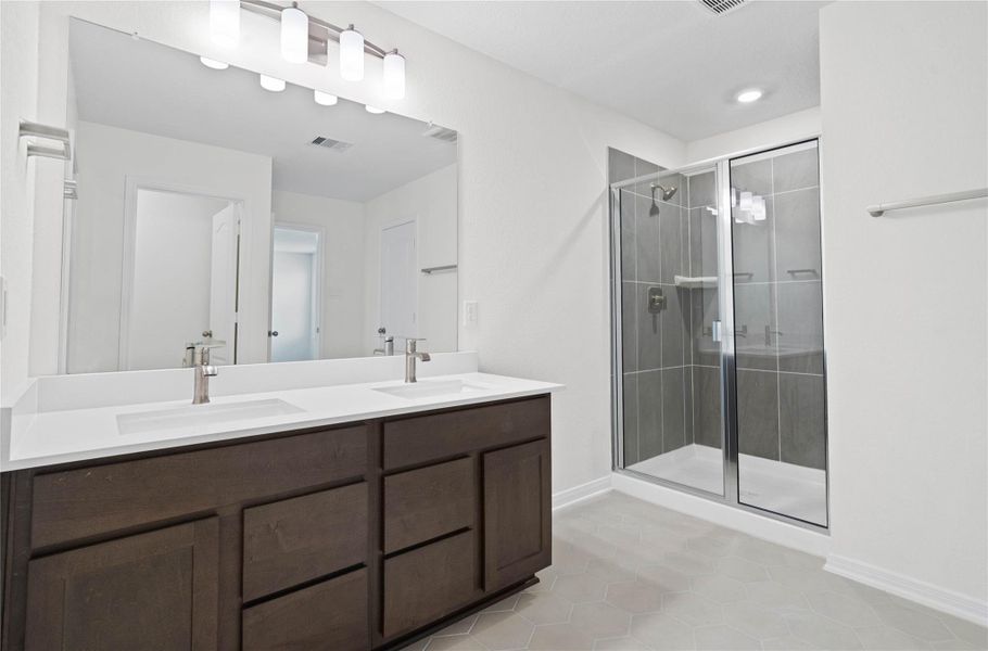This move-in ready primary bathroom offers a spacious walk-in shower with seat and tile surround, stained cabinetry topped with light countertops, dual sinks, high ceilings, neutral paint, a large mirror, and sleek, modern finishes for a polished look. This move-in ready primary bathroom offers a spacious walk-in shower with seat and tile surround, stained cabinetry topped with light countertops, dual sinks, high ceilings, neutral paint, a large mirror, and sleek, modern finishes for a polished look.