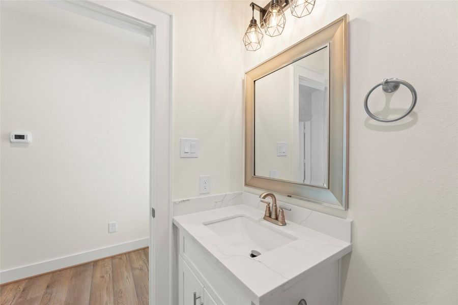 This photo showcases a modern bathroom with a sleek white vanity, quartz countertop, and a stylish mirror. The room features elegant lighting fixtures and a neutral color palette, creating a clean and inviting space.