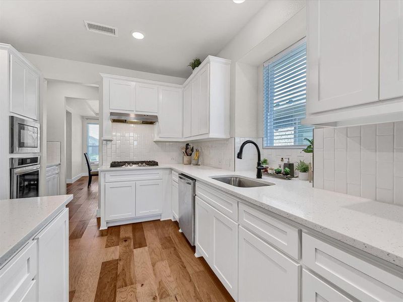 Kitchen with sink, white cabinetry, stainless steel appliances, and a healthy amount of sunlight Kitchen with sink, white cabinetry, stainless steel appliances, and a healthy amount of sunlight