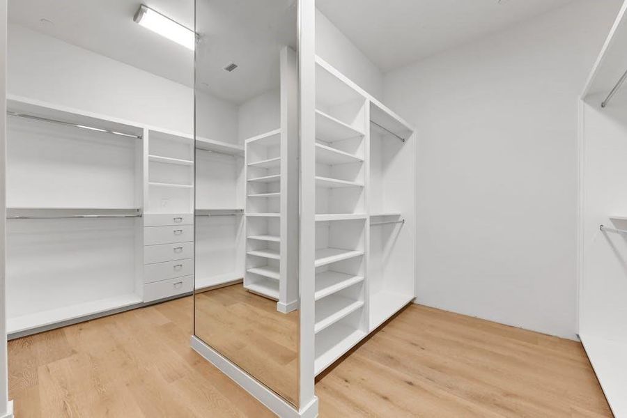 Large primary closet with floor to ceiling mirror