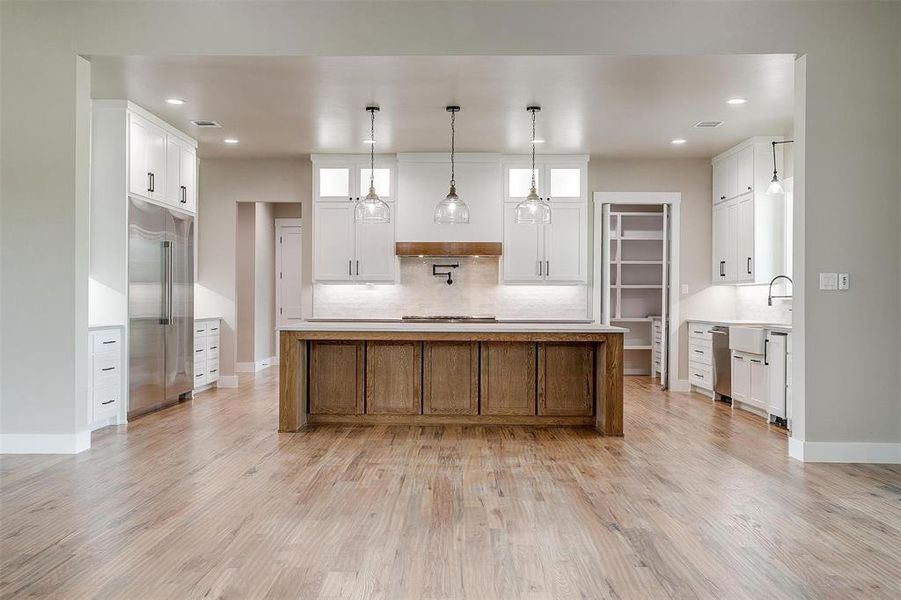 Kitchen featuring high end fridge, tasteful backsplash, light wood-type flooring, recessed lighting, and baseboards Kitchen featuring high end fridge, tasteful backsplash, light wood-type flooring, recessed lighting, and baseboards