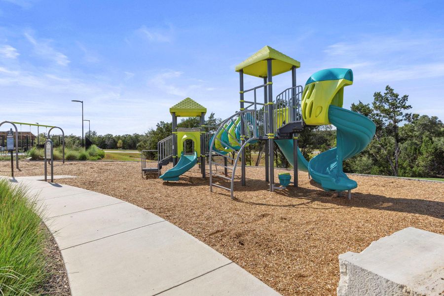 Concrete walkways lead to a modern neighborhood recreation park with extensive play structures.