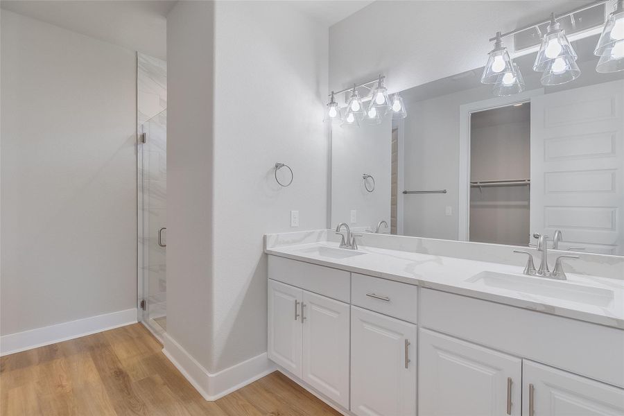 Primary bath featuring dual vanity, quartz countertops, modern fixtures, large walk in closet, and floor-to-ceiling shower tile Primary bath featuring dual vanity, quartz countertops, modern fixtures, large walk in closet, and floor-to-ceiling shower tile