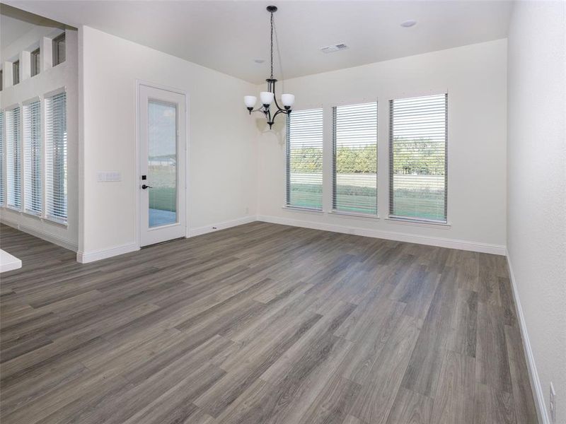 Unfurnished dining area featuring a chandelier and wood finished floors Unfurnished dining area featuring a chandelier and wood finished floors