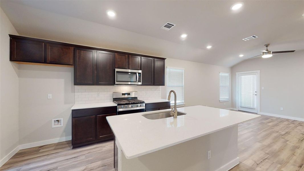 A well-appointed kitchen features rich cabinetry, quartz countertops, and a central island with a sink. A well-appointed kitchen features rich cabinetry, quartz countertops, and a central island with a sink.