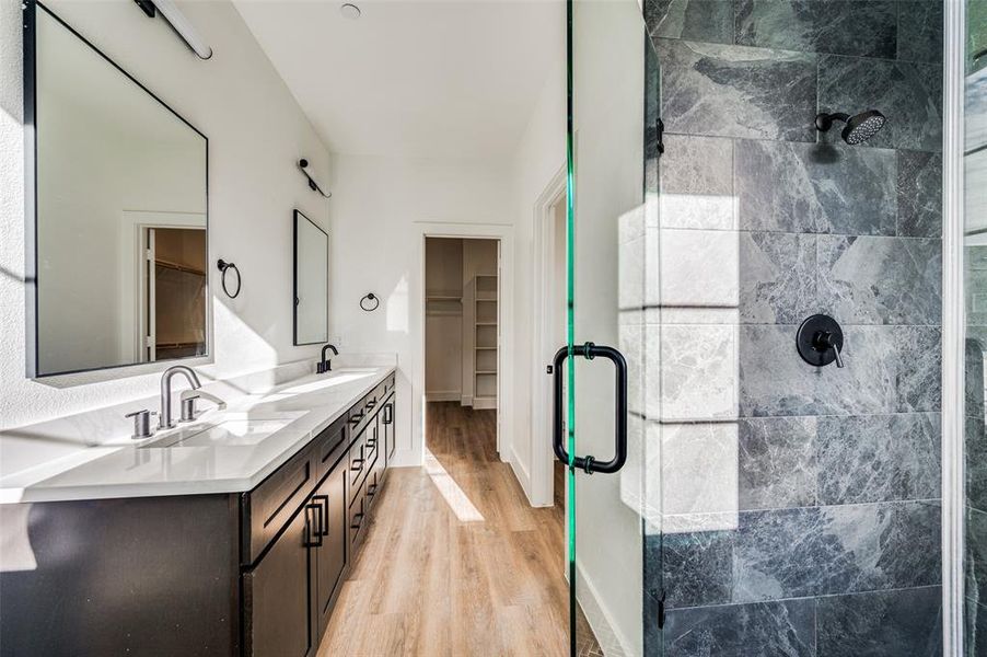 Bathroom with walk in shower, vanity with extensive cabinet space, double sink, and wood-type flooring