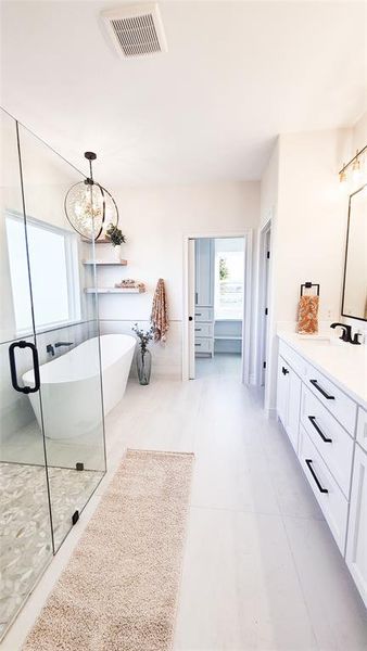 Bathroom with tile patterned flooring, vanity, a tub, and a chandelier