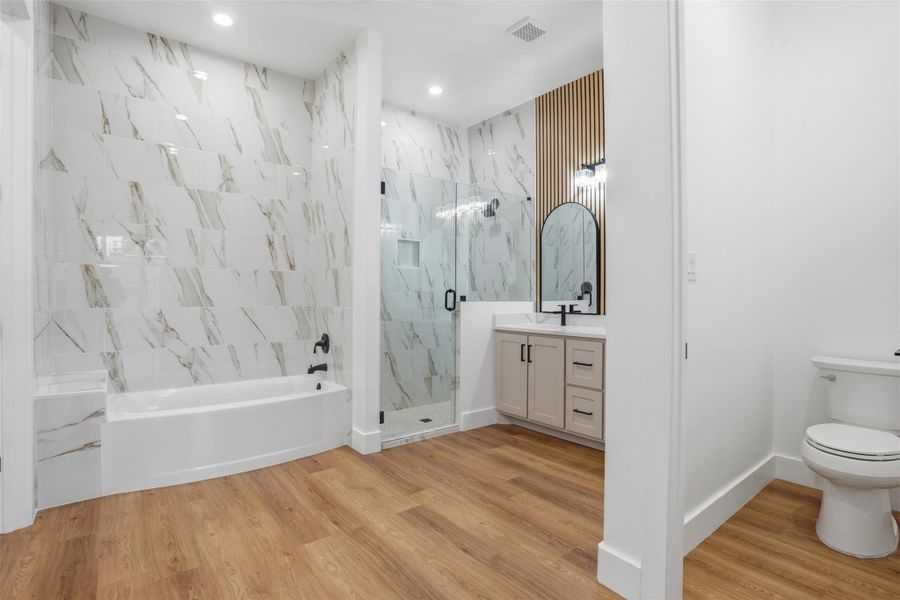 Bathroom featuring vanity, a garden tub, a marble finish shower, and light wood-type flooring