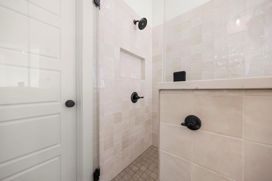 Step into this contemporary shower, featuring light-toned tile walls and sophisticated matte black fixtures.