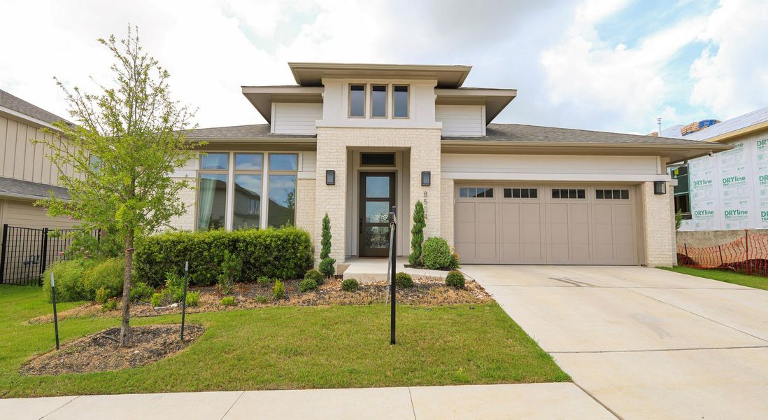 A modern architectural gem showcases an inviting front entry, pristine landscaping, and an attached two-car garage. A modern architectural gem showcases an inviting front entry, pristine landscaping, and an attached two-car garage.