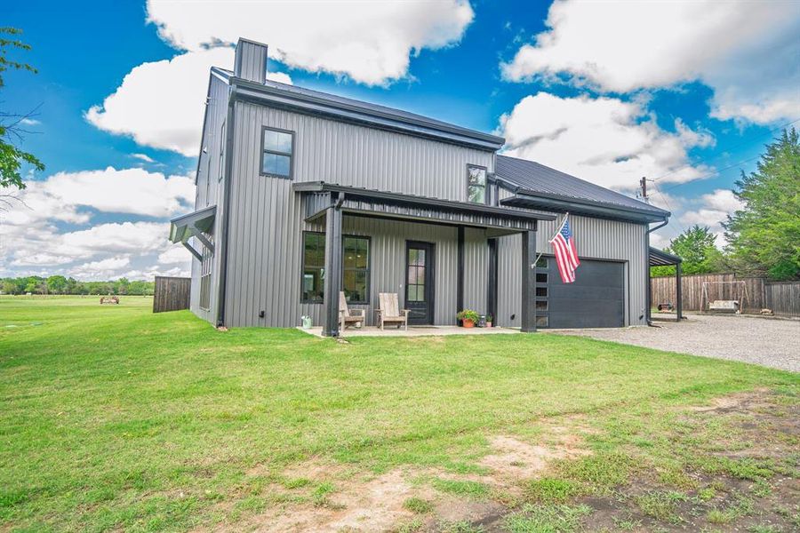 Rear view of house featuring gravel driveway and a garage Rear view of house featuring gravel driveway and a garage