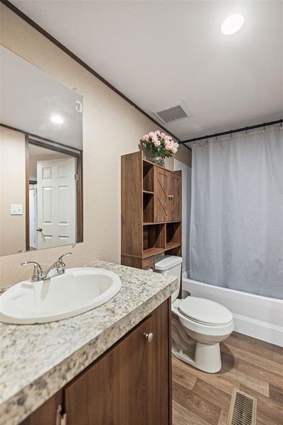 Bathroom featuring a wood-finish vanity with a light speckled countertop, undermount sink, and chrome faucet Bathroom featuring a wood-finish vanity with a light speckled countertop, undermount sink, and chrome faucet