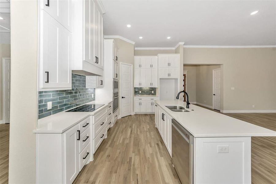 Kitchen featuring sink, white cabinets, an island with sink, and light hardwood / wood-style flooring