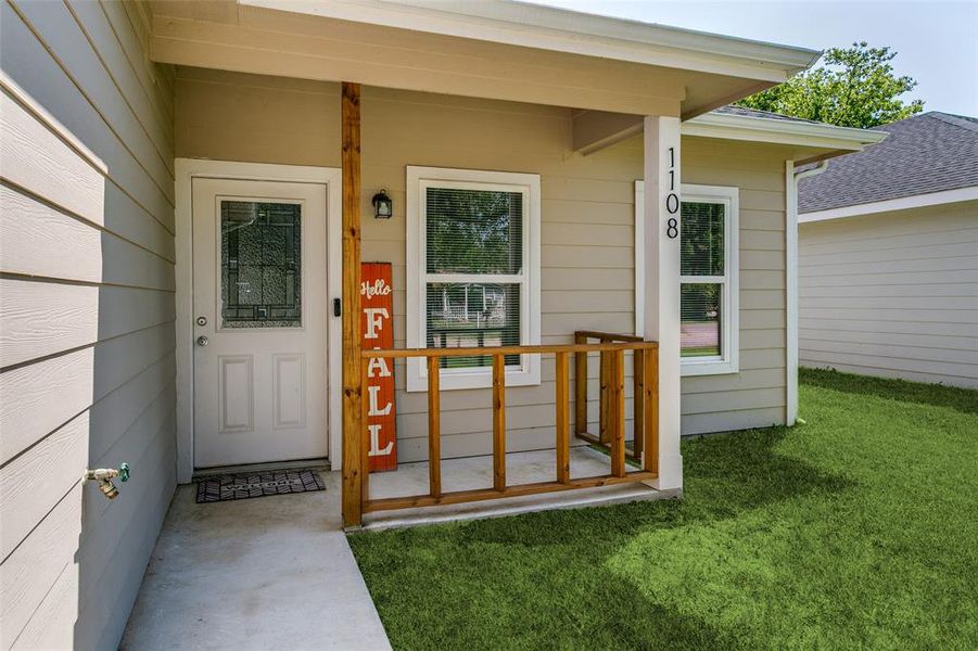 View of exterior entry featuring a porch and a lawn View of exterior entry featuring a porch and a lawn