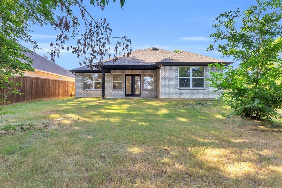 Back of property with french doors, brick siding, and a shingled roof