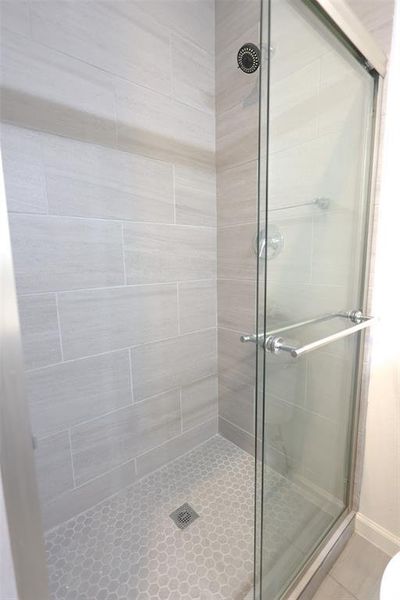 Bathroom featuring a shower stall and tile patterned flooring