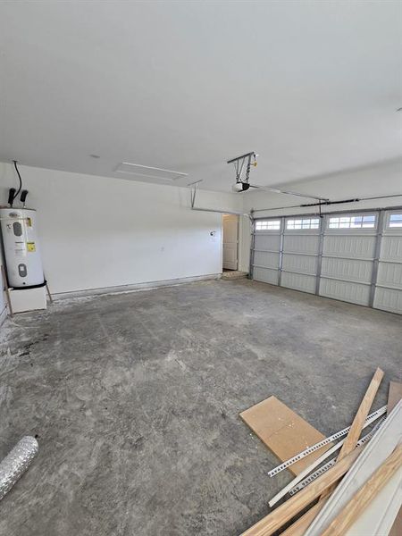 Garage featuring a garage door opener and electric water heater