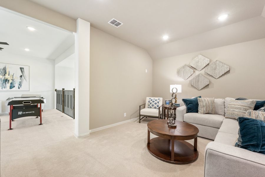 Upstairs loft with sectional sofa, round coffee table, and air hockey table on carpet