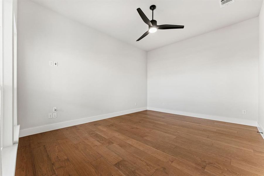 Empty room with hardwood / wood-style floors and ceiling fan