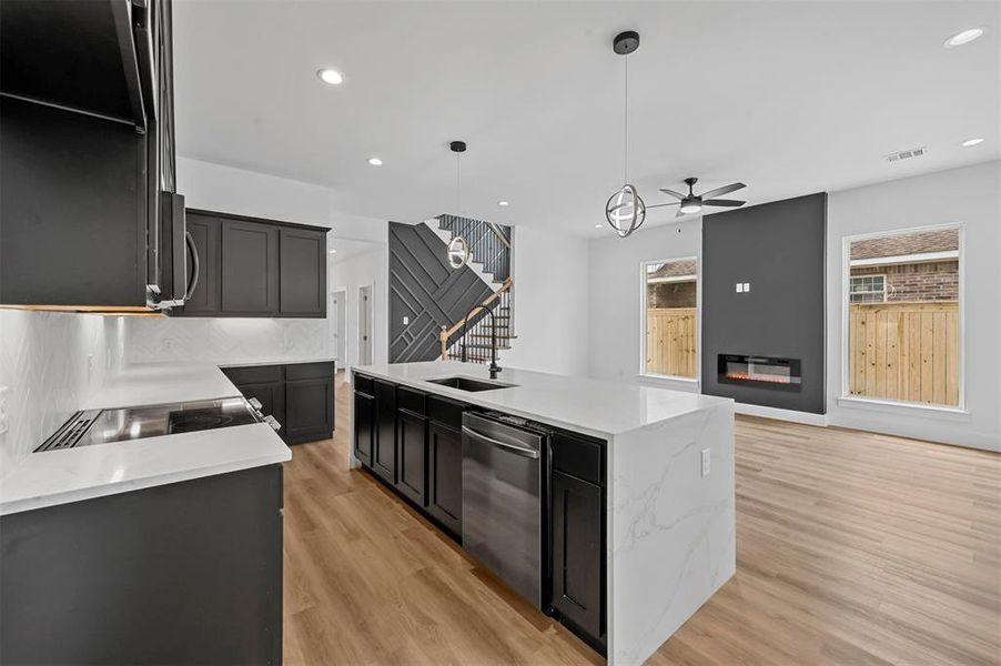 Kitchen with ceiling fan, a center island with sink, light hardwood / wood-style floors, and stainless steel appliances