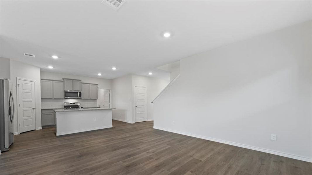 Kitchen featuring gray cabinets, stainless steel appliances, a center island with sink, recessed lighting, and dark wood-style floors Kitchen featuring gray cabinets, stainless steel appliances, a center island with sink, recessed lighting, and dark wood-style floors