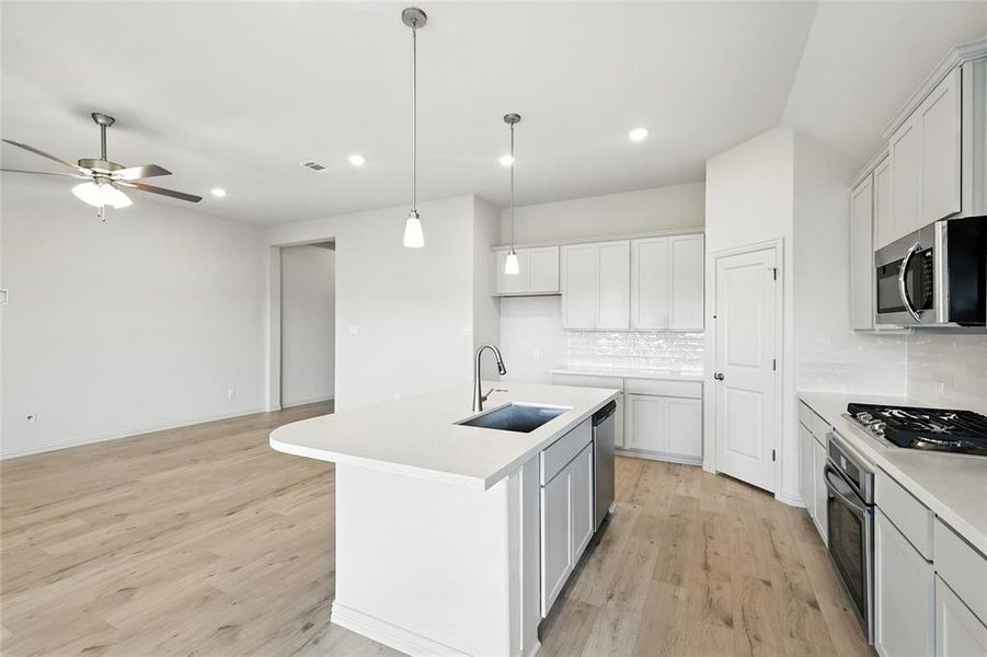 Kitchen featuring a center island with sink, decorative light fixtures, tasteful backsplash, light wood-style flooring, and recessed lighting Kitchen featuring a center island with sink, decorative light fixtures, tasteful backsplash, light wood-style flooring, and recessed lighting