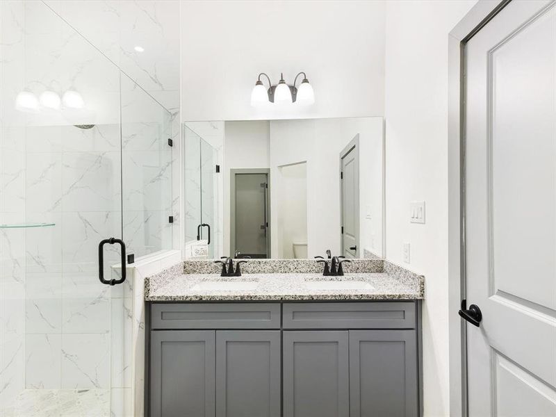 Bathroom featuring double vanity and a marble finish shower Bathroom featuring double vanity and a marble finish shower
