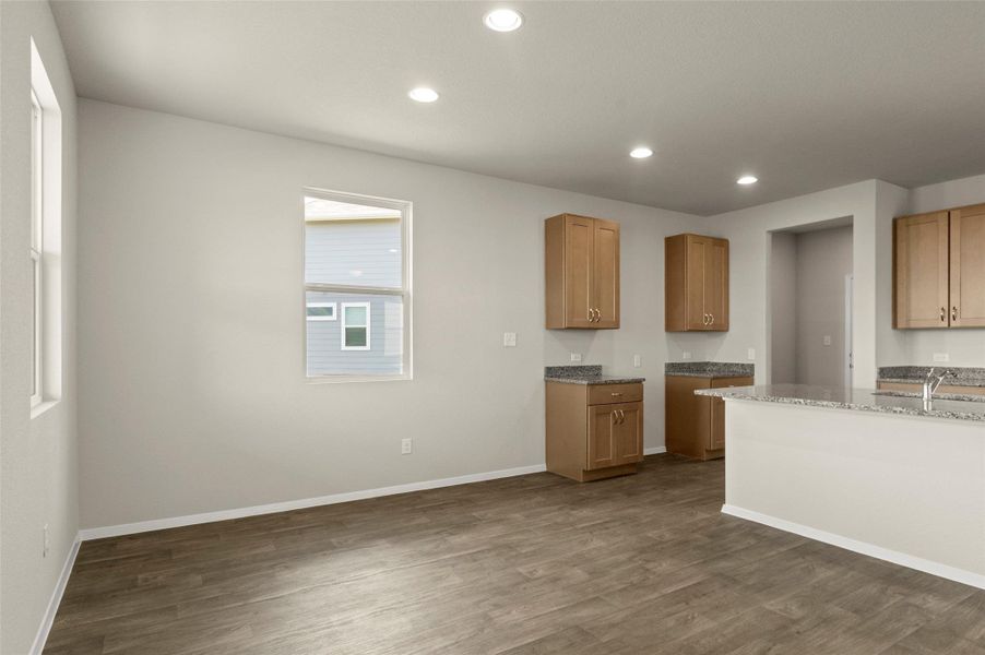 Kitchen with dark wood-style floors, recessed lighting, and light stone counters