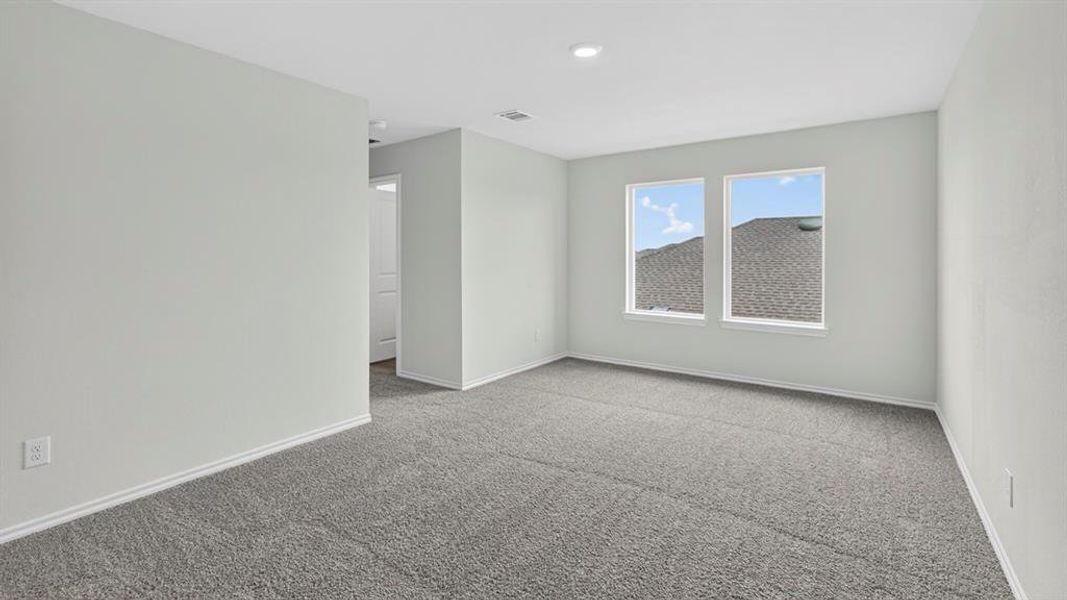 Spacious room featuring gray wall-to-wall carpeting, recessed lighting, and two windows providing exterior light Spacious room featuring gray wall-to-wall carpeting, recessed lighting, and two windows providing exterior light