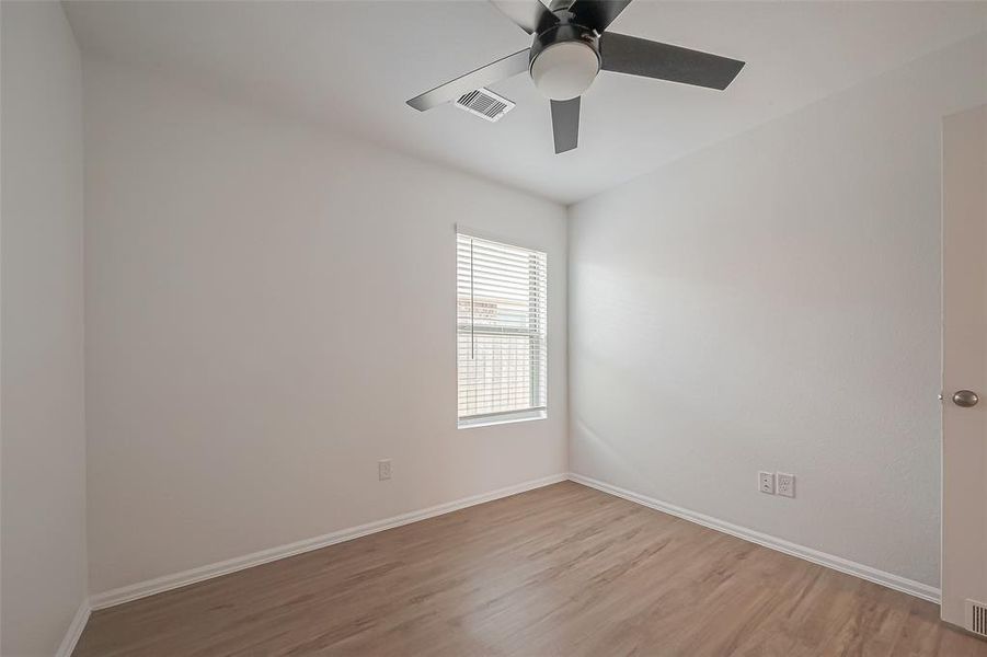 Another view of the first guest bedroom reveals a light and bright space, filled with abundant natural light from the window.