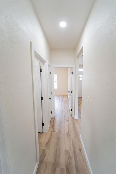 Interior hallway with wood-finish flooring, recessed lighting, and crisp white walls