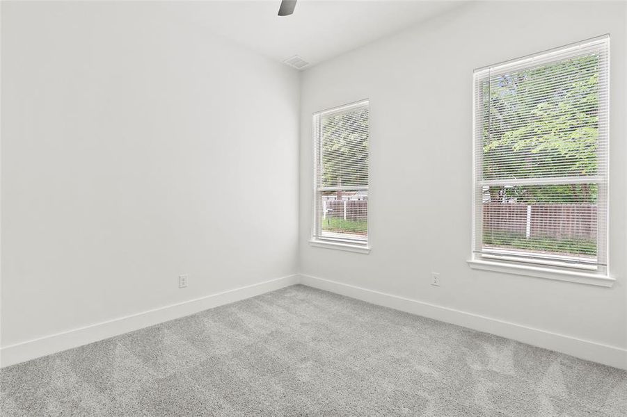 Carpeted room featuring two windows with white blinds, white walls, and a ceiling fan