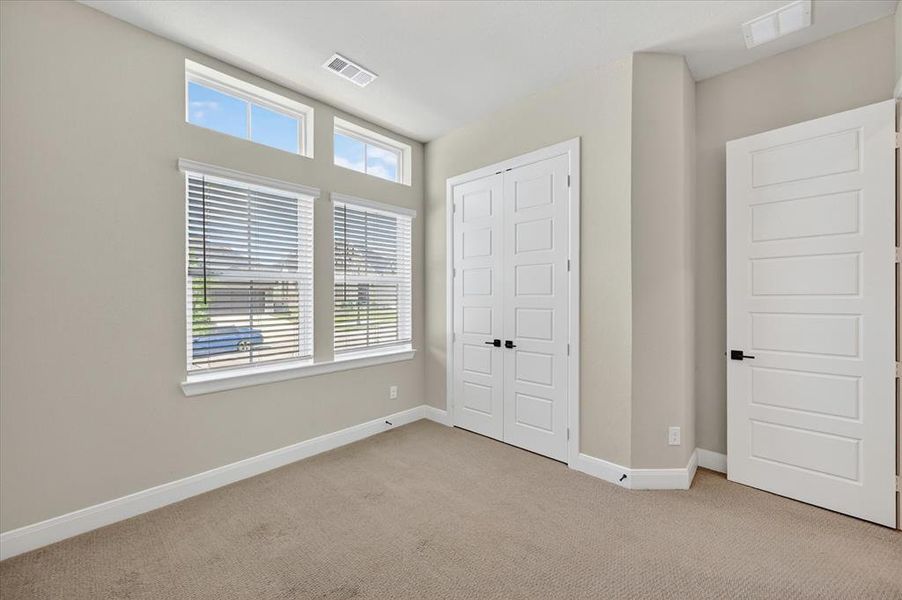 Carpeted room featuring multiple windows with blinds, transom windows, neutral wall tones, and white trim Carpeted room featuring multiple windows with blinds, transom windows, neutral wall tones, and white trim