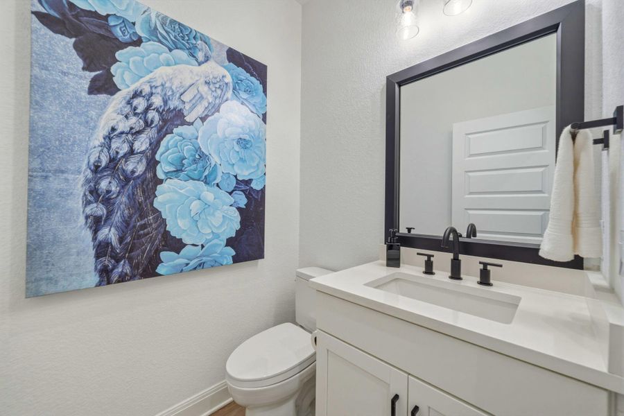 Downstairs powder bathroom featuring a contemporary vanity with an integrated sink and white countertop