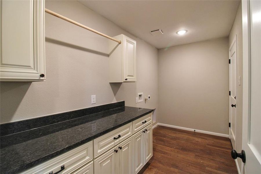 Laundry area featuring dark wood finished floors, hookup for a washing machine, and cabinet space