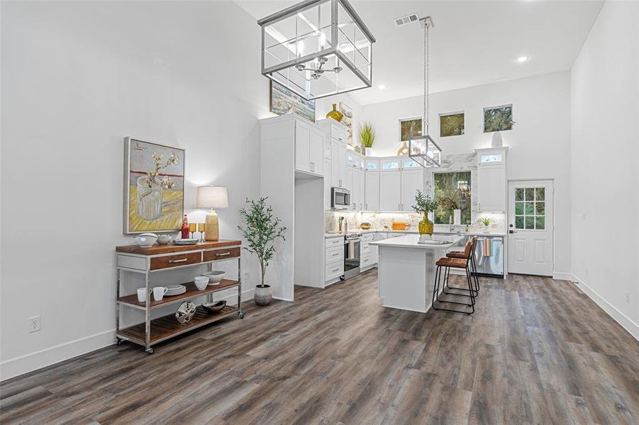 Kitchen featuring stainless steel appliances, white cabinetry, a center island, and dark wood-type flooring