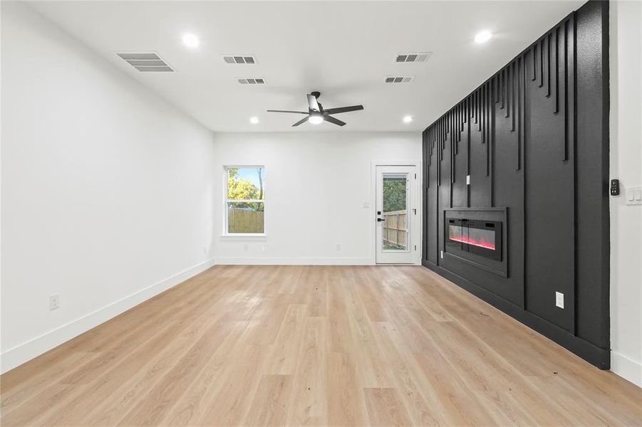 Unfurnished living room with a large fireplace, recessed lighting, light wood-type flooring, and a ceiling fan Unfurnished living room with a large fireplace, recessed lighting, light wood-type flooring, and a ceiling fan