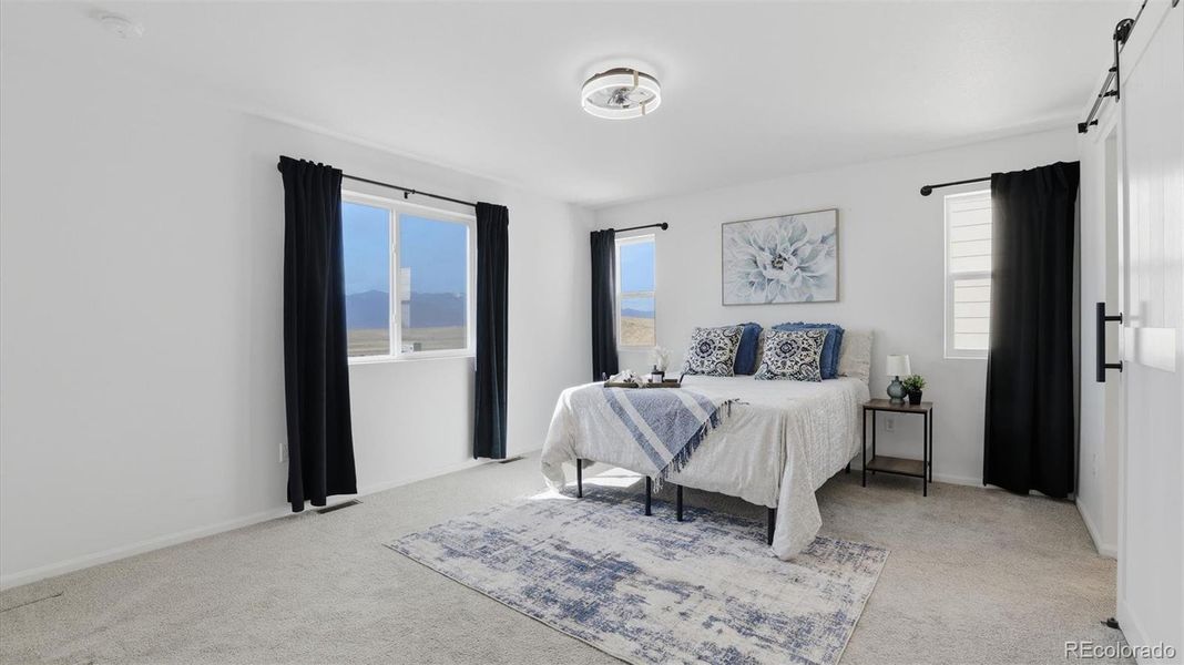 The upper level Primary Retreat has a ceiling fan, neutral carpet, and windows with mountain views.