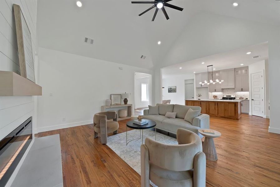 Living area featuring recessed lighting, light wood finished floors, a fireplace, high vaulted ceiling, and ceiling fan Living area featuring recessed lighting, light wood finished floors, a fireplace, high vaulted ceiling, and ceiling fan