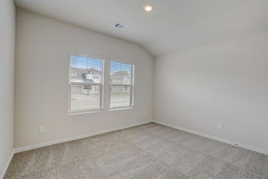 Carpeted empty room featuring vaulted ceiling