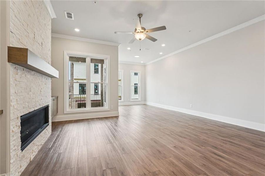 Unfurnished living room featuring a fireplace, crown molding, dark wood-type flooring, ceiling fan, and recessed lighting