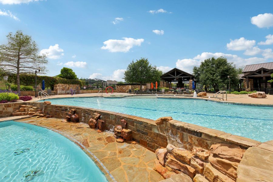 The community features a large outdoor swimming pool with stone accents, surrounded by a paved patio area