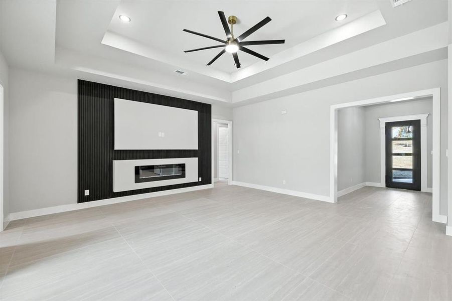 Unfurnished living room with a tray ceiling, a ceiling fan, light tile patterned floors, and recessed lighting Unfurnished living room with a tray ceiling, a ceiling fan, light tile patterned floors, and recessed lighting