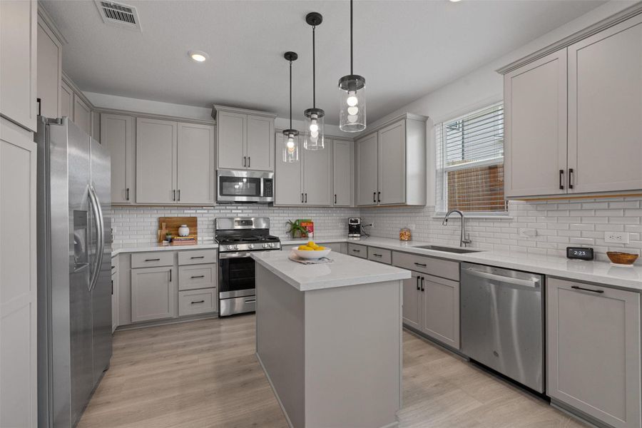 Kitchen featuring stainless steel appliances, gray cabinets, center island, and recessed lighting
