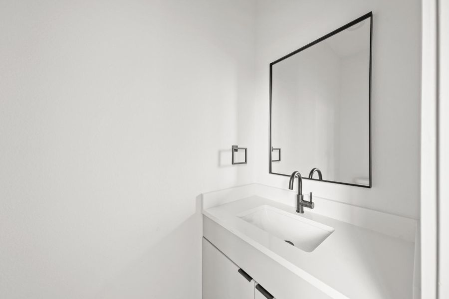 The second floor half bath is conveniently located at the top of the stairwell and features tile floors, a sleek vanity with quart counter complemented by a black framed mirror and a matching black faucet. The second floor half bath is conveniently located at the top of the stairwell and features tile floors, a sleek vanity with quart counter complemented by a black framed mirror and a matching black faucet.